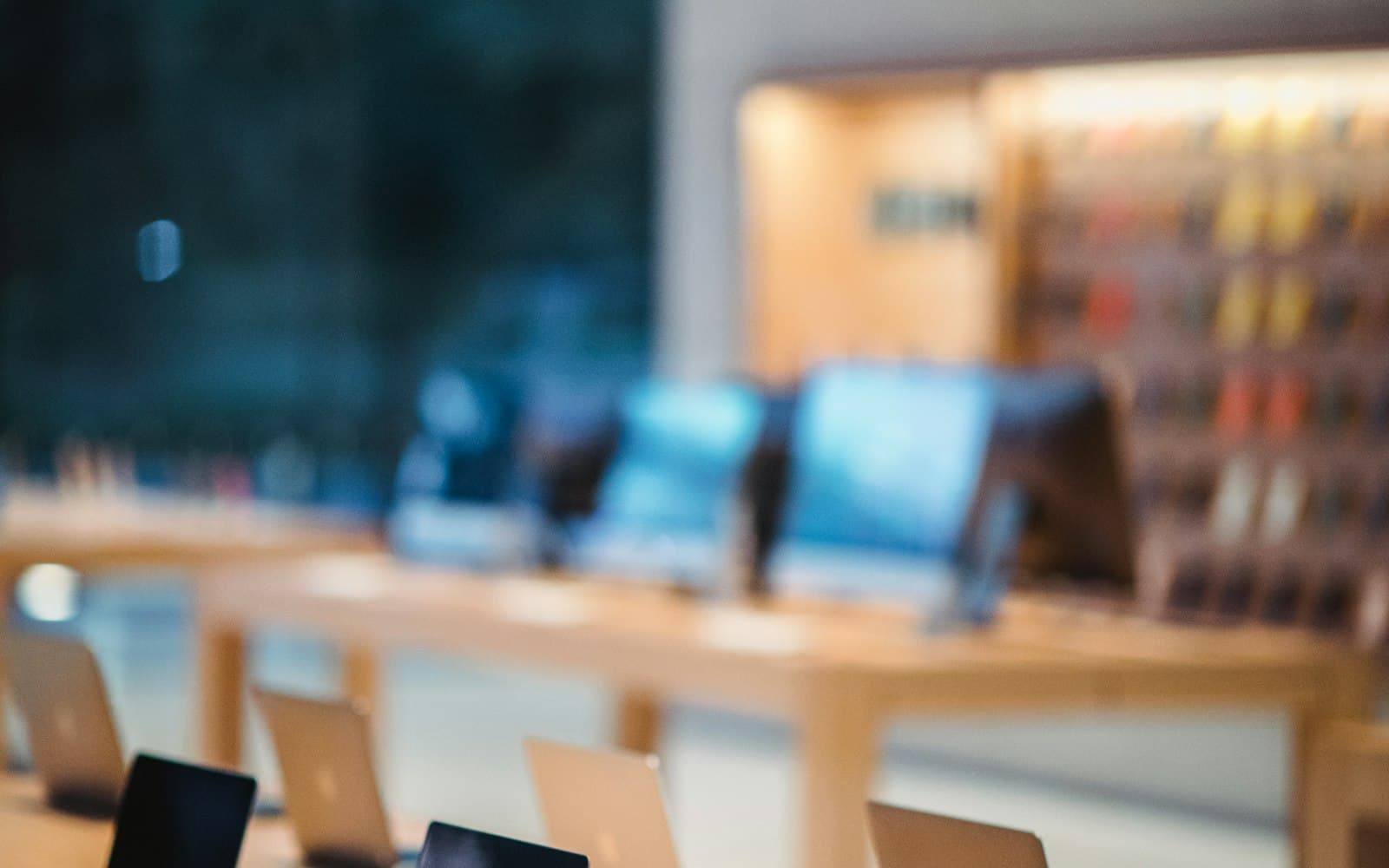 A computer shop interior with laptops on display tables and an accessory wall.